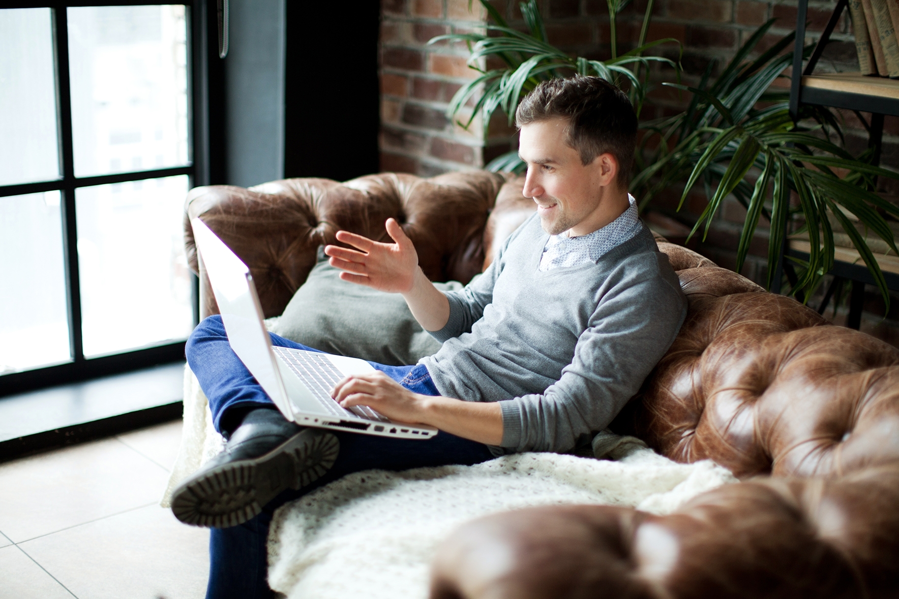 Adult learner sitting on a couch using a laptop for a Berlitz private online Mandarin lesson.